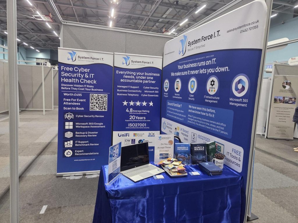 The System Force IT stand showing the 60-second Cyber Risk Score quiz, a laptop and free IT guides